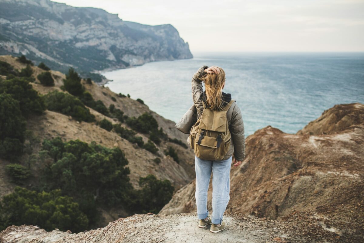 Backpacker hippie woman happy to enjoy amazing sea and mountain view from hill