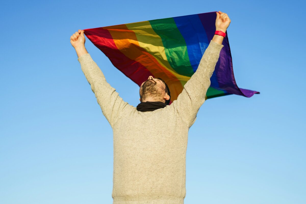 Gay man in the countryside with LGBT flag raised