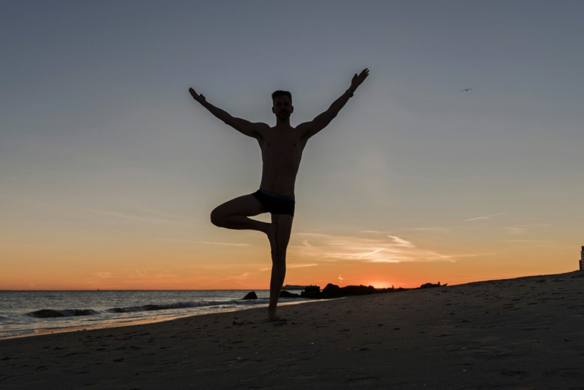 Man doing beach yoga at dusk